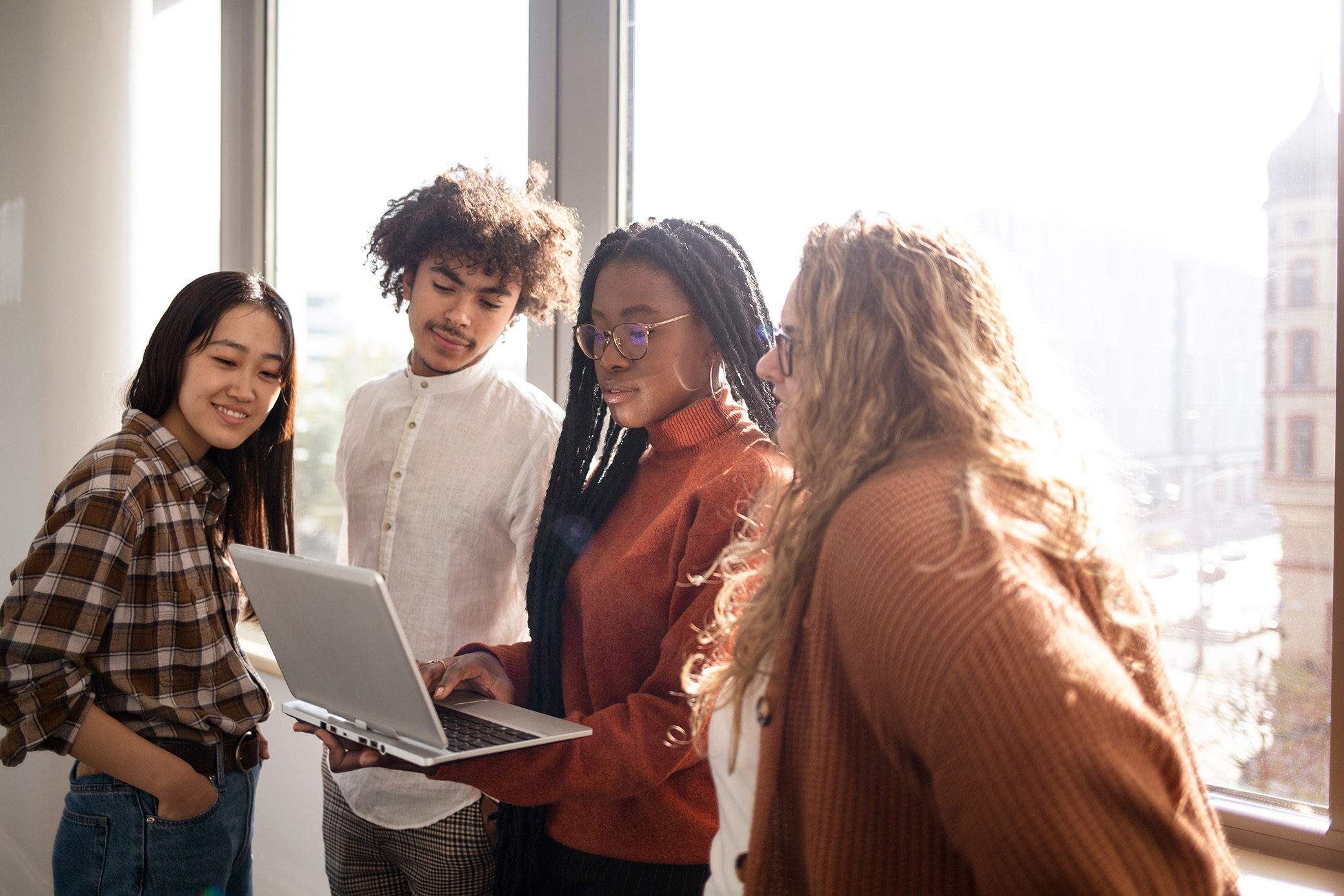 Four young professionals looking at a laptop.