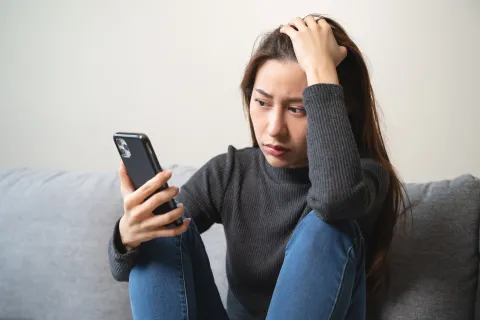 Person looks at phone with concern